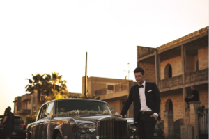 a groom standing in front of a limousine